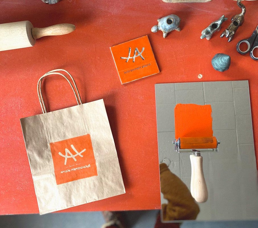 Amalie branding the bags with orange ink for sales. The stamp was hand-carved by Amalie and hand-printed by her as well