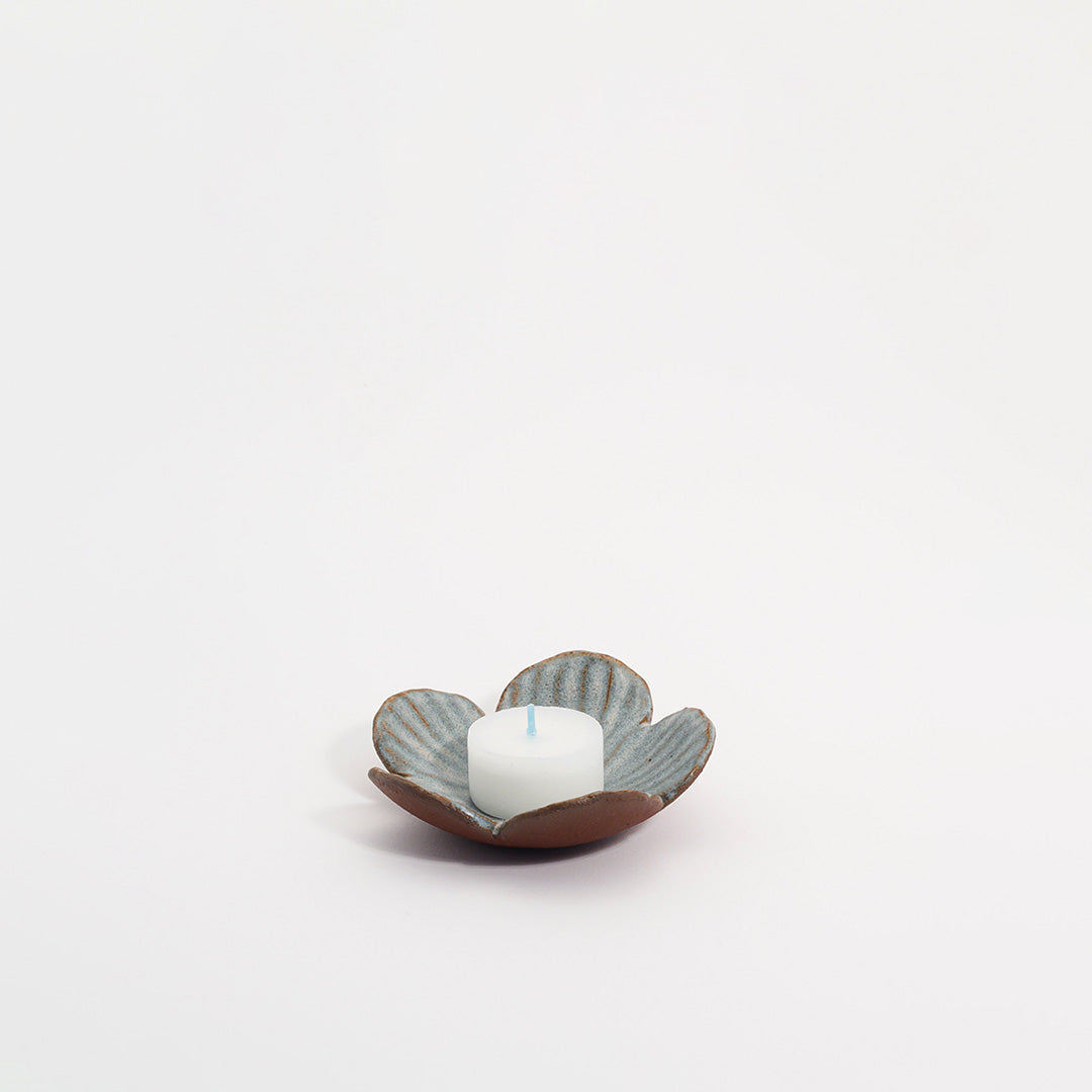 lille blomsterskål med en blå glasur, der holder et lille lys